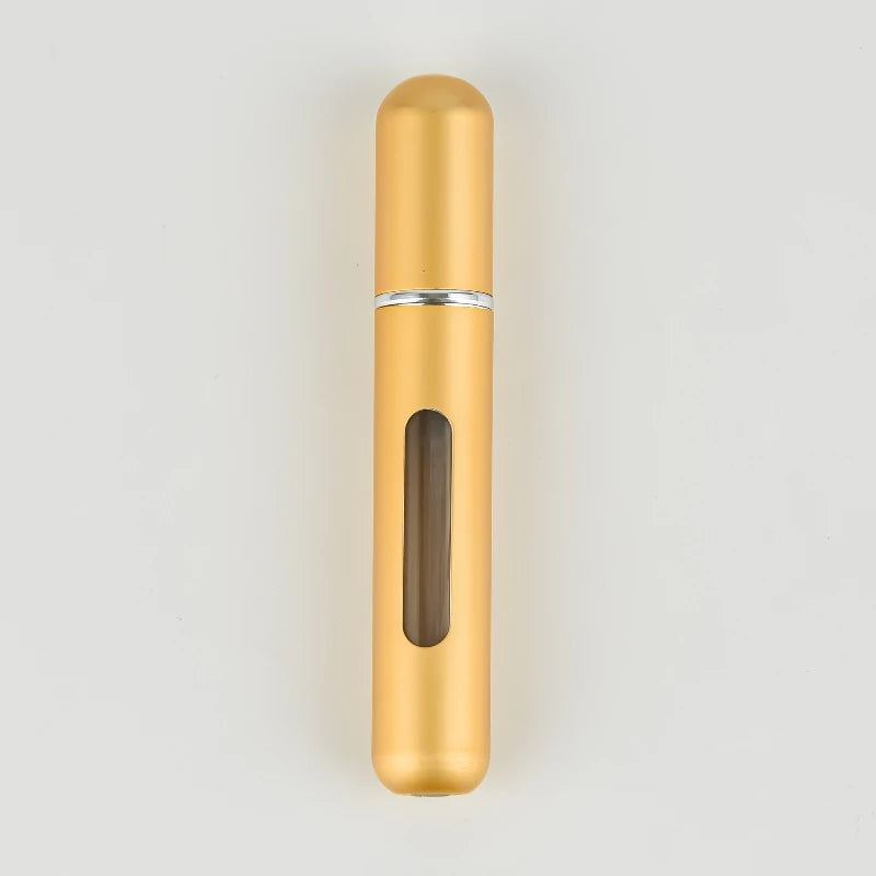 A tall, cylindrical gold-colored portable refillable perfume bottle with a silver band and a glass insert.