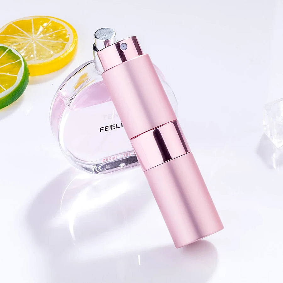 Une bouteille de parfum rose en verre et un distributeur assorti sont montrés à côté d'une tranche de citron et de lime.