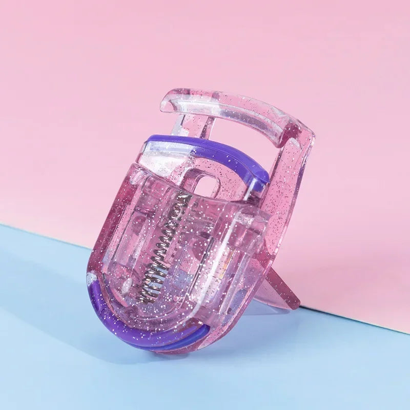 A pink and purple mini folding eyelash curler set resting on a light blue surface.