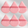 Un set de six éponges de maquillage triangulaires roses avec des élastiques roses.