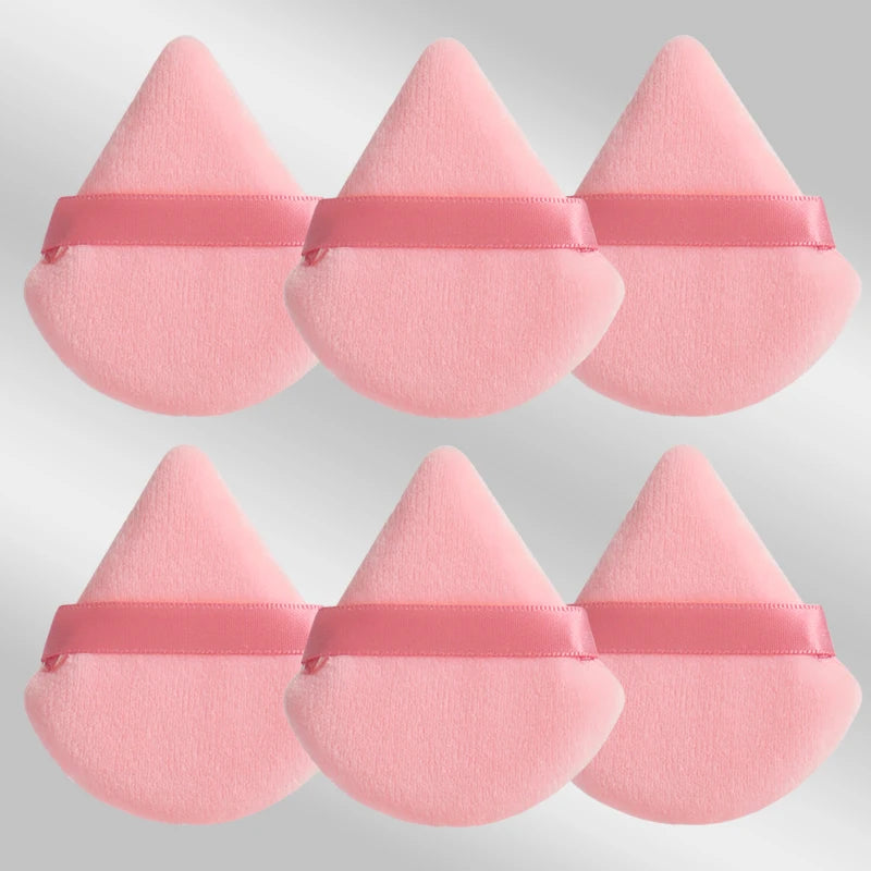 Un set de six éponges de maquillage triangulaires roses avec des élastiques roses.