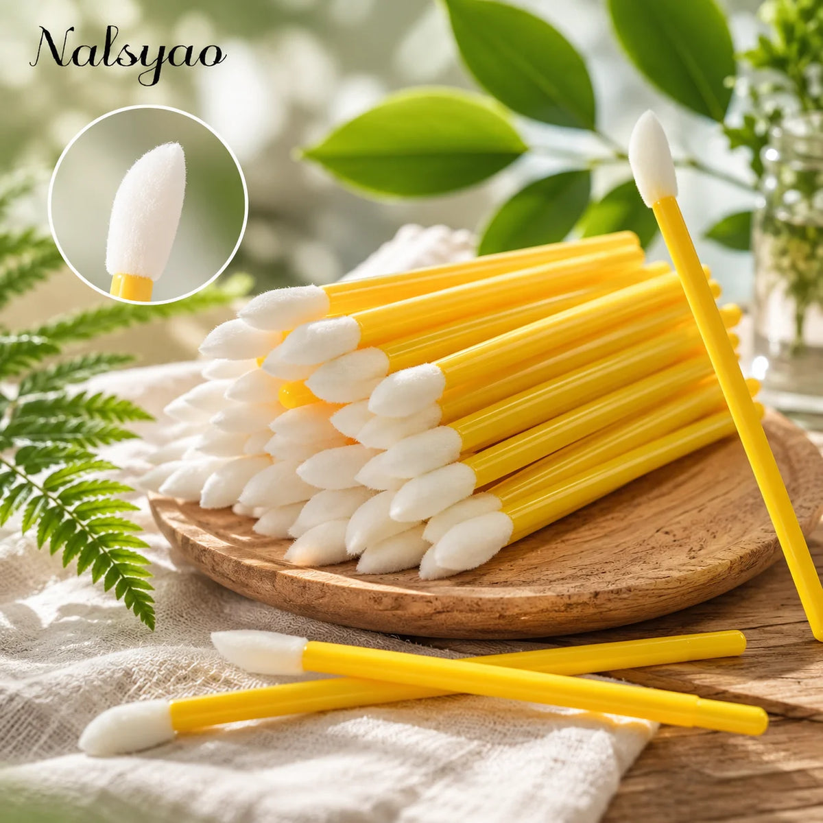 A wooden board holds a large set of yellow and white disposable lip applicator brushes with a small white brush shown in deta