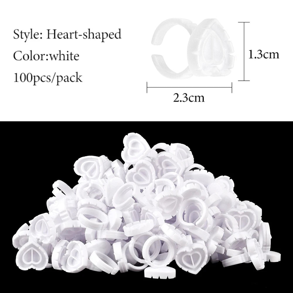 A pile of white heart-shaped disposable glue rings for eyelash extensions and nail art