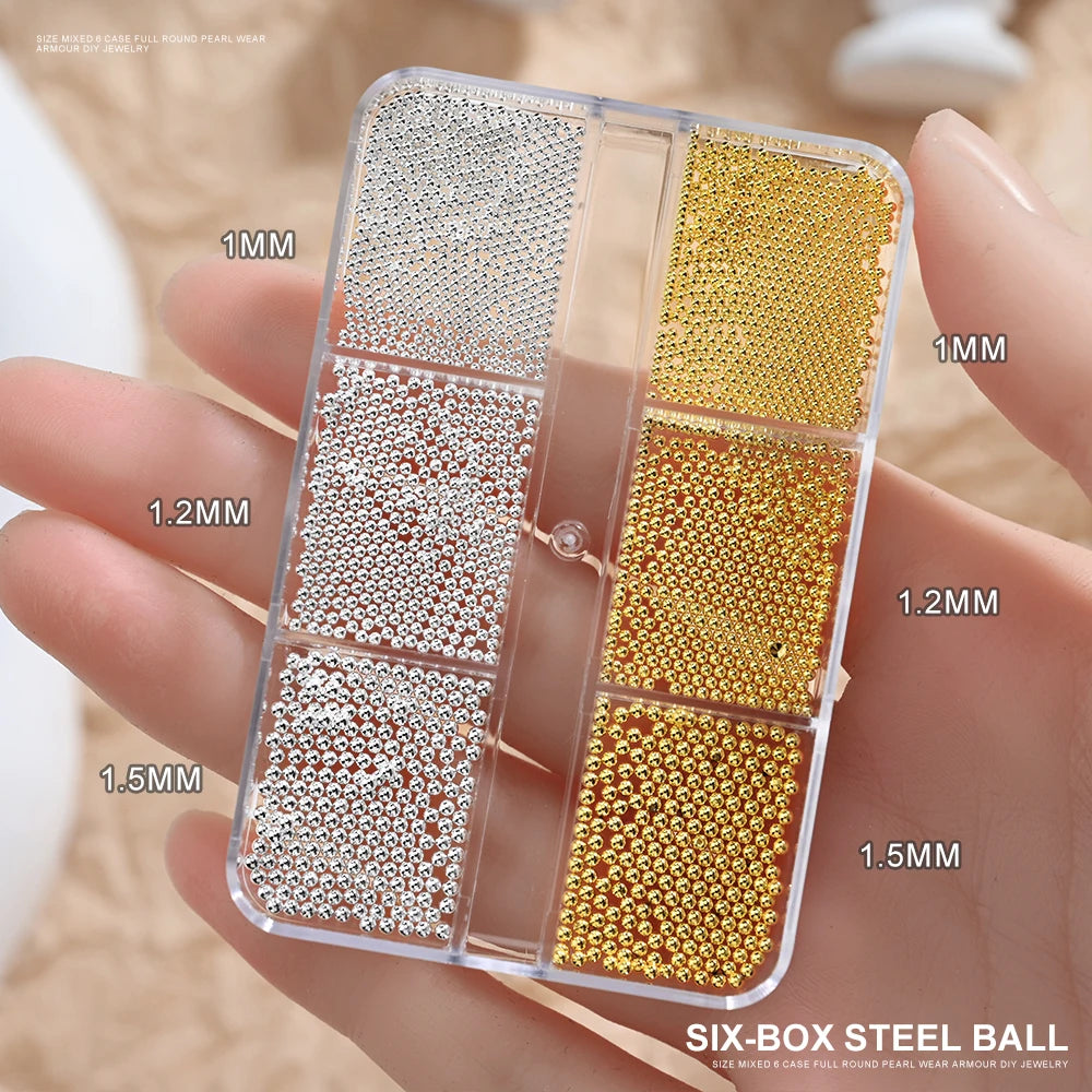 A clear six-box case of gold mixed stainless steel beads for nail art decorations shown in a hand.