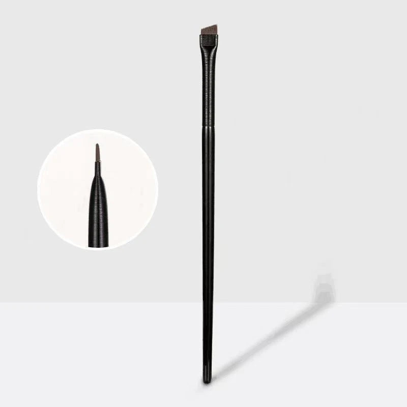 A single black professional angled makeup brush standing vertically against a light gray background.