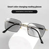 A pair of black reading glasses with a gold frame resting on a white display stand.