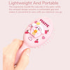 A hand holds a pink cartoon mini air cushion massage comb with fruit and heart designs.
