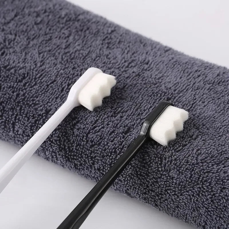 A black and white ultra-fine bristle toothbrush set resting on a gray towel.