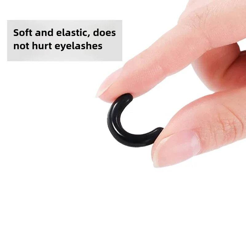 A hand is shown using a black silicone eyelash curler pad to curl eyelashes.