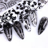 Un ensemble de autocollants pour ongles en dentelle noir et blanc sur fond blanc.