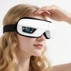 A woman is using a white portable Bluetooth eye massager with vibration and music on her eye.
