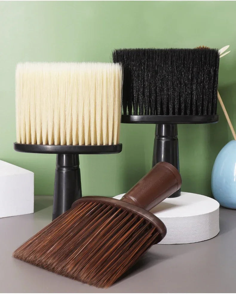 A set of black and cream soft bristle hair duster brushes displayed on a gray surface.
