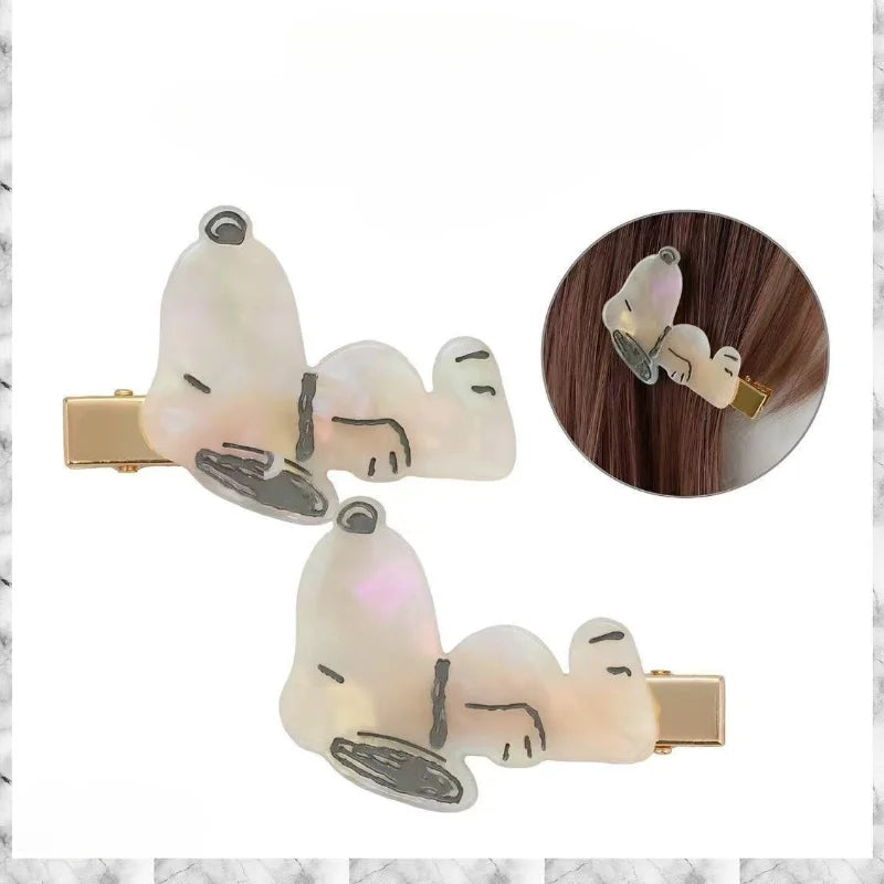 A set of two white cartoon Snoopy hair clips featuring black outlines and gold accents.