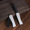 A pair of foldable anti-static steel combs for hair, beard, and wigs resting on a dark wooden surface.