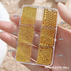A clear box holds various sizes of gold mixed stainless steel beads for nail art decorations.