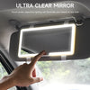 Une main touche l'écran tactile lumineux d'un miroir de vanité monté dans l'intérieur d'une voiture.