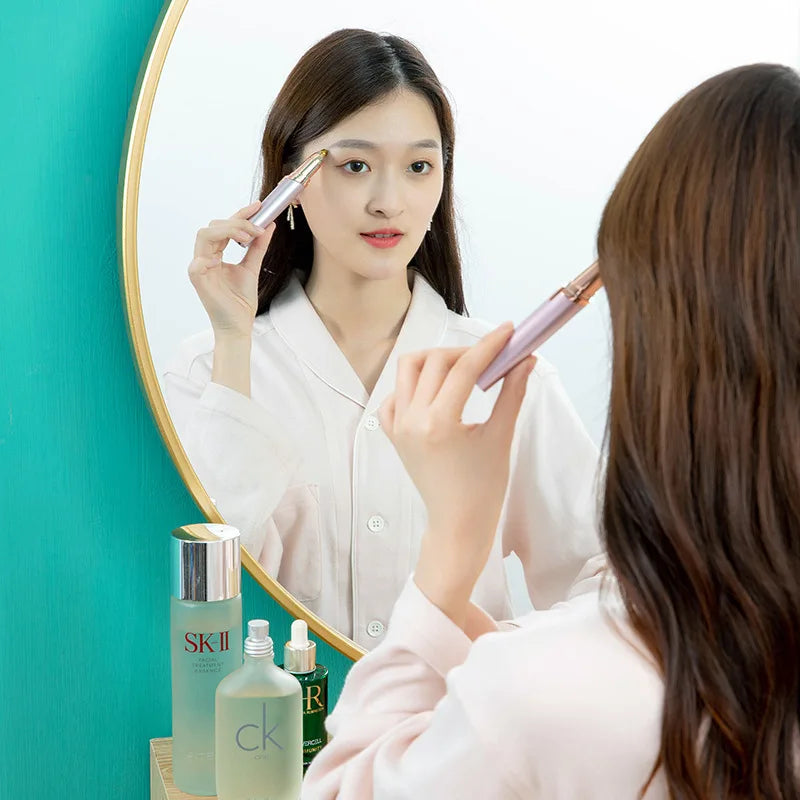 A woman is using a precision electric eyebrow trimmer to shape her eyebrows in front of a mirror.