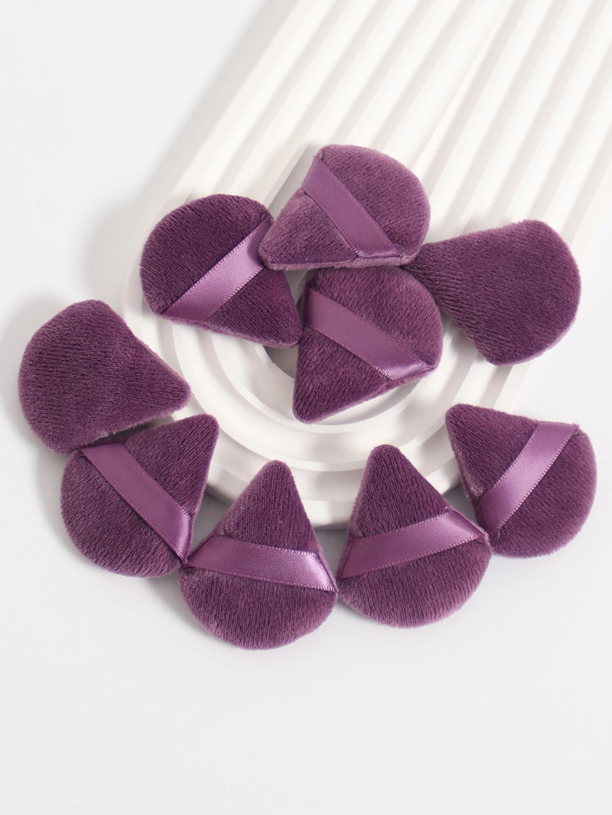 Un ensemble de puffs triangulaires violets avec des rubans satinés sur une surface blanche.
