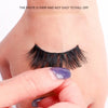 A hand is applying a dark black eyelash glue to a false lash, demonstrating the paste is firm and not easy to fall off.