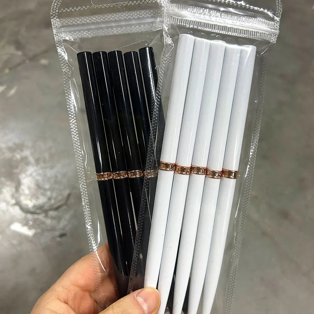 Un emballage plastique transparent contenant un set de pinceaux pour liner de nail art noir et blanc avec accents dorés.