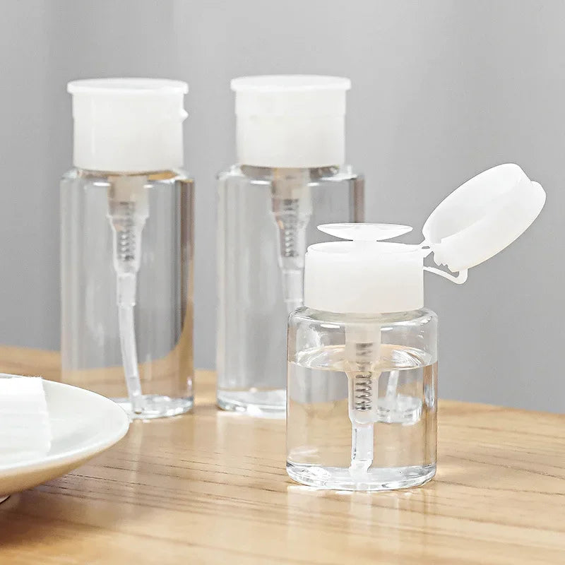 Three clear glass bottles with white pump dispensers are displayed on a wooden surface.