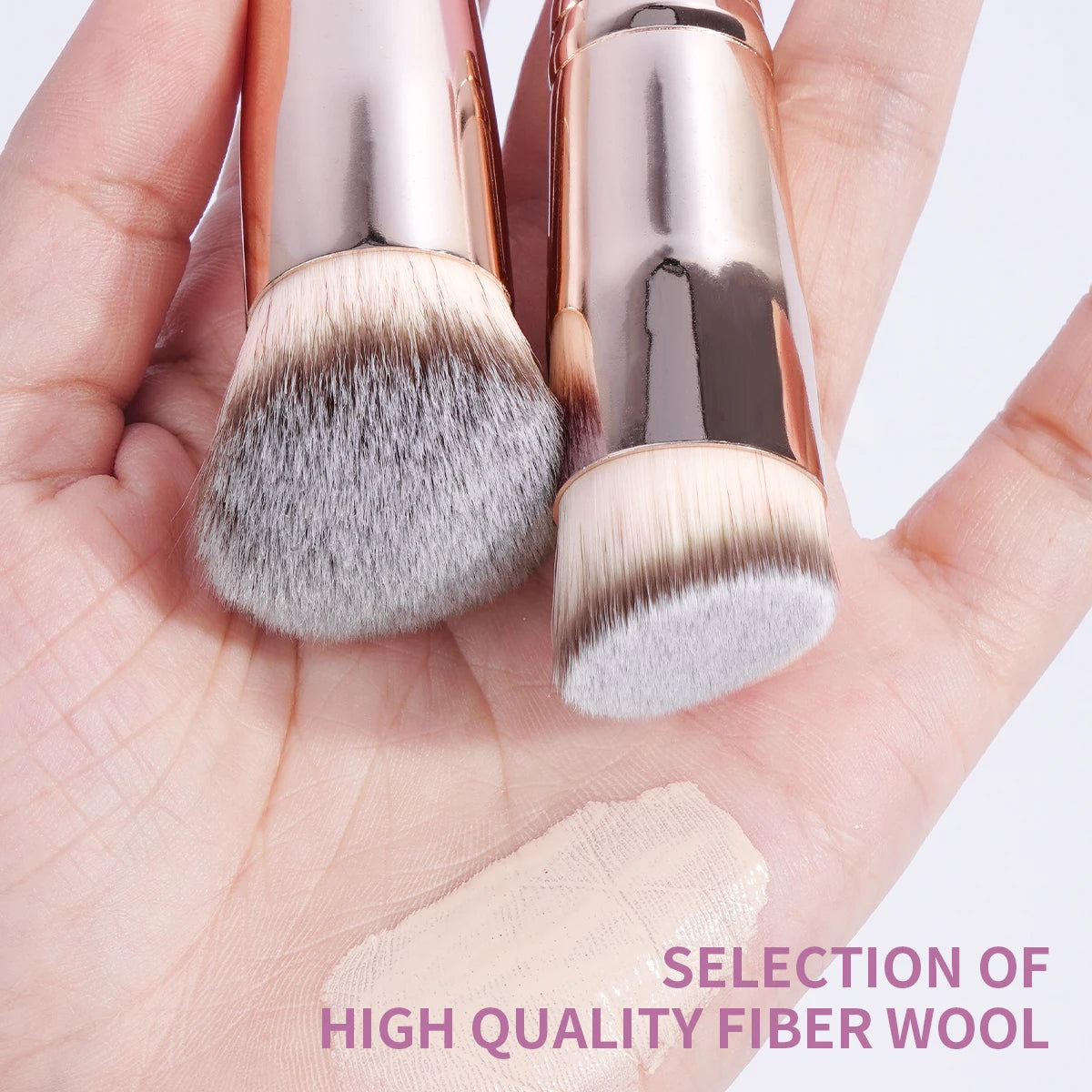 A hand holds a set of professional makeup brushes featuring soft gray and blonde fiber wool bristles.