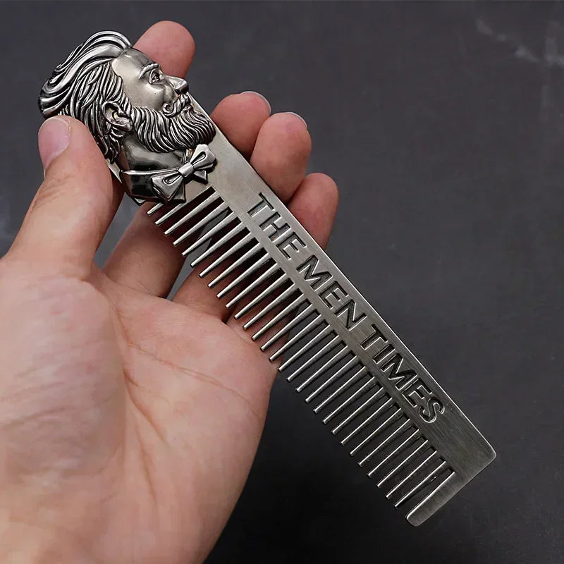 A hand holds a silver beard and mustache comb with a sculpted face design.
