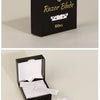 A black box containing 100 pieces of razor blades is shown next to loose white razor blades.