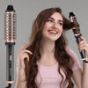 A woman is using an electric hair curling comb to style her long brown hair.