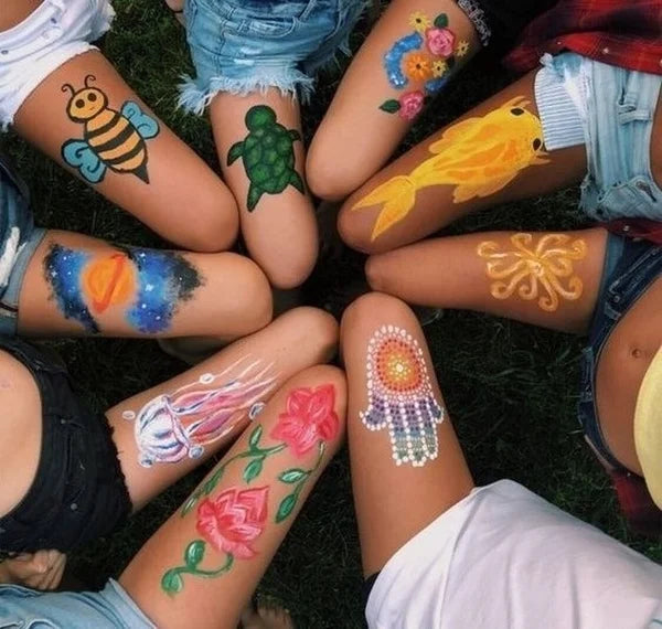 Gros plan sur les bras et les jambes de plusieurs personnes décorés de peintures colorées visage et corps.