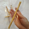 Eine Hand hält eine natürliche Miswak-Zahnbürste in klarem Plastik für die Mundpflege.