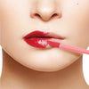 A close-up of a woman's mouth with bright red lipstick being applied by a pink lip wand.