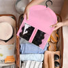 A pink wig storage bag with a hanger is shown inside a brown storage box next to a straw hat and clothing.