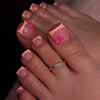 A close-up of a hand displaying press-on fake nails with a short square French design featuring pink and floral accents.