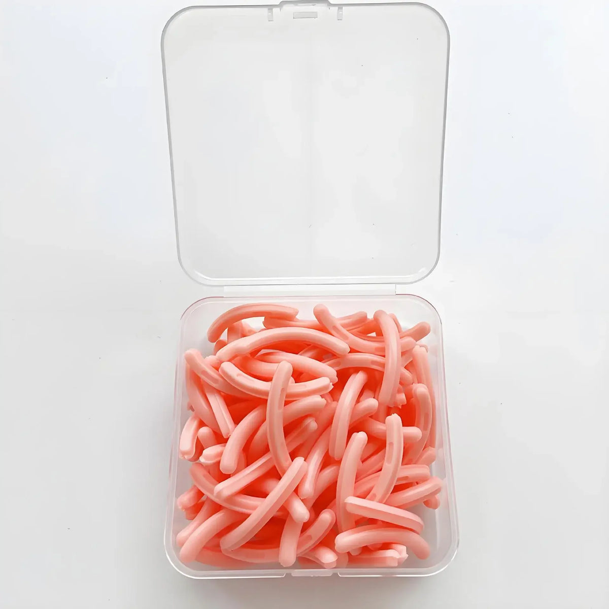 A clear plastic container filled with 30 pink silicone eyelash curler pads.