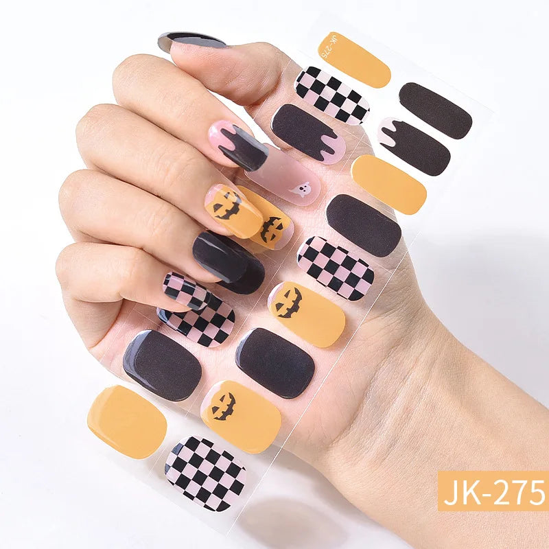 A hand displays various Halloween UV gel nail stickers in black, pink, and orange shades on a clear plastic sheet.