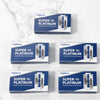 Tres cajas de cuchillas de afeitar de acero inoxidable FlagDear Super Tool Platinum expuestas sobre una superficie de mármol 