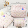 Pink quilted cotton makeup bag with zipper closure shown next to measuring tape and cosmetic brush.