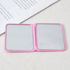 A pink portable makeup mirror with a reflective surface, shown open on a white background.
