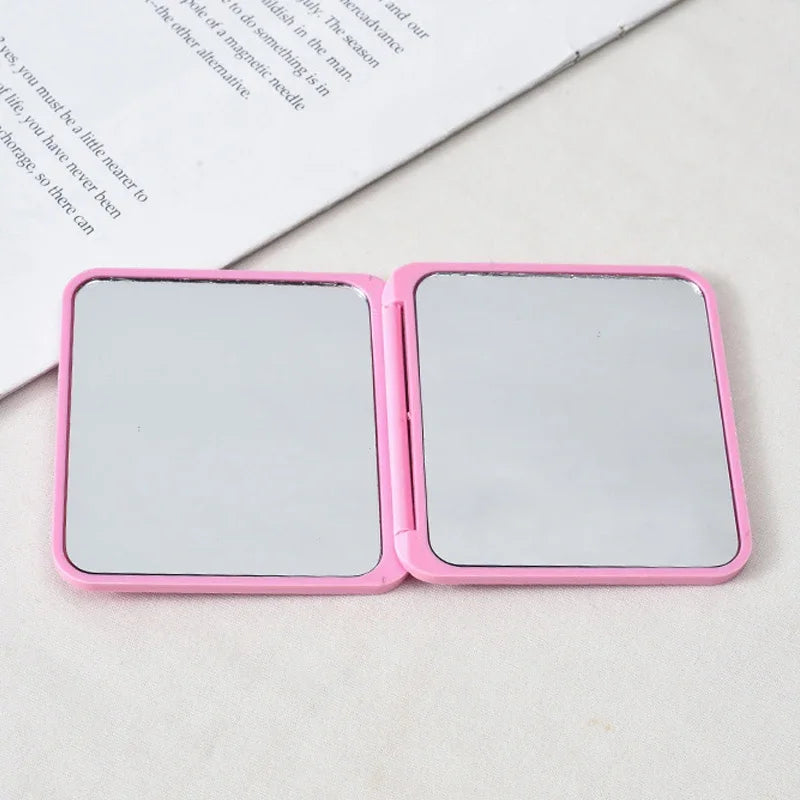 A pink portable makeup mirror with a reflective surface, shown open on a white background.