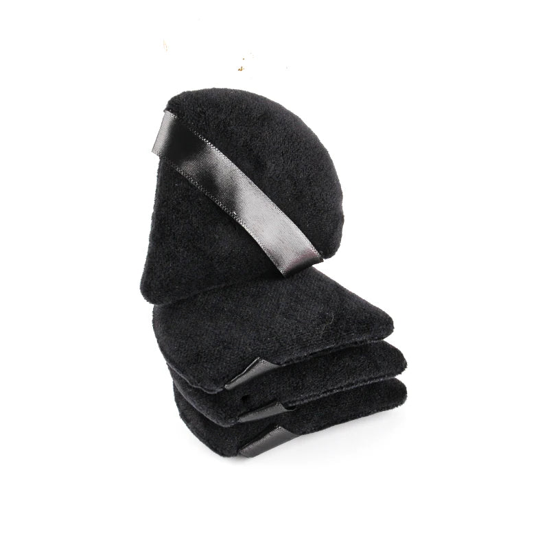 A stack of black velvet powder puffs with satin ribbon accents.