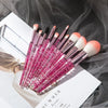 A set of ten professional makeup brushes with pink and purple bristles laid on a white background.
