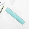 A light mint green exfoliating mesh body scrubbing towel rolled up on a white surface.