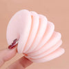 A hand holds a stack of soft pink velvet makeup puffs for concealer and powder.