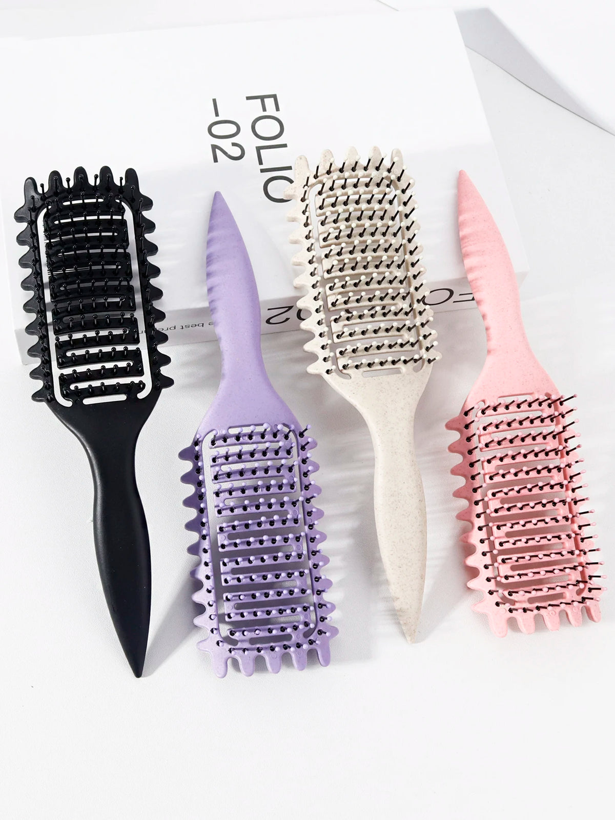 Un ensemble de trois peignes pour cheveux bouclés professionnels noir, violet et rose sur fond blanc.