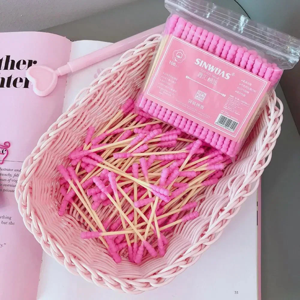 Un contenant rose contient un paquet de cotons-tiges en bambou rose pour un nettoyage doux.