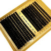 A gold-framed box containing lash clusters for DIY eyelash extensions, showing various lengths of black false lashes.