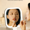 A woman uses a 4K HD mirror to apply makeup, showing clear skin and brightness.