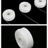 White dental floss spool with thin white floss visible on a black background.