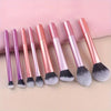 A set of eight pink and purple makeup brushes with fluffy silicone bristles displayed on a light background.
